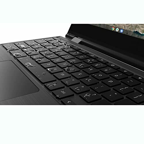 Close-up of a laptop keyboard with water droplets.